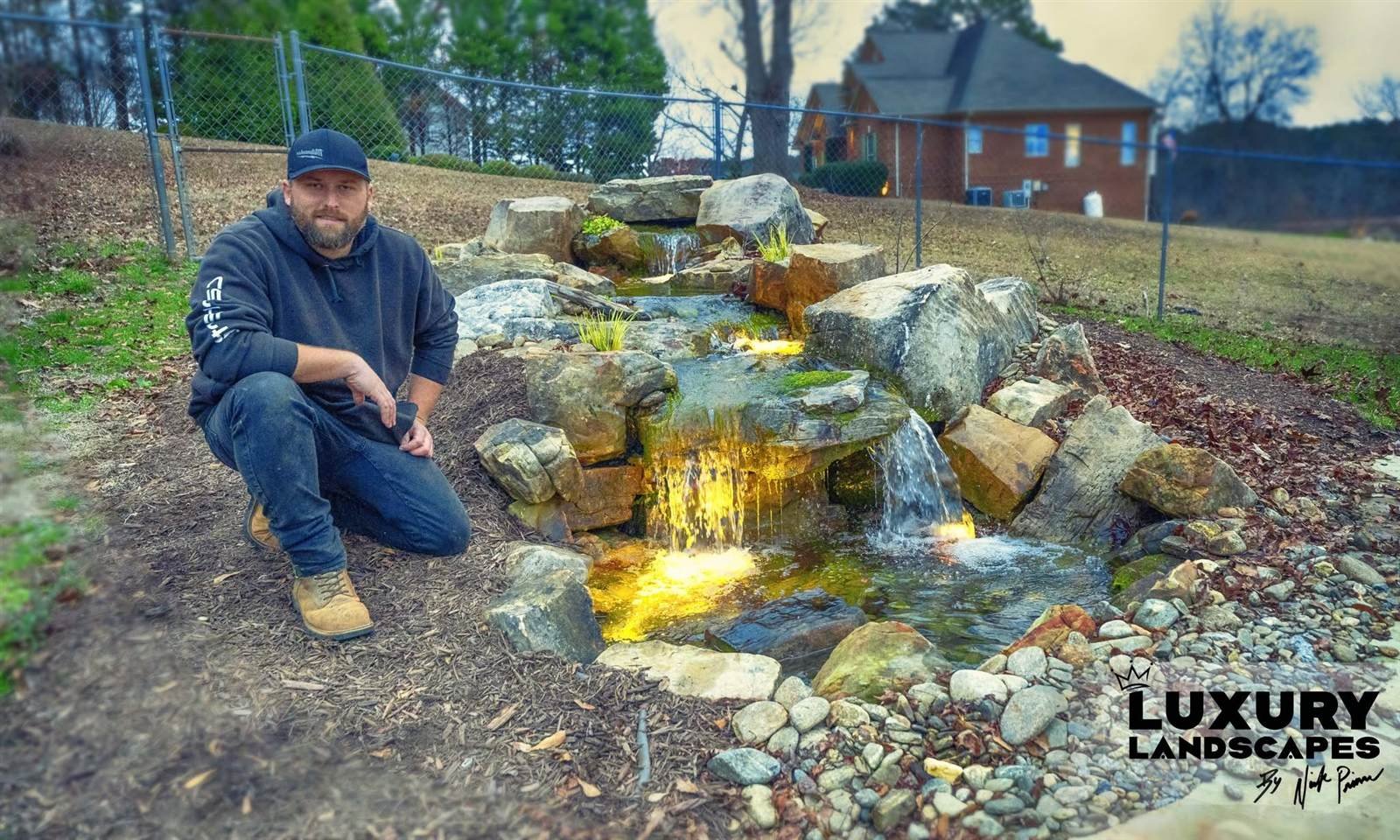 Nick Prince, owner of Luxury Landscapes, beside a completed backyard waterfall