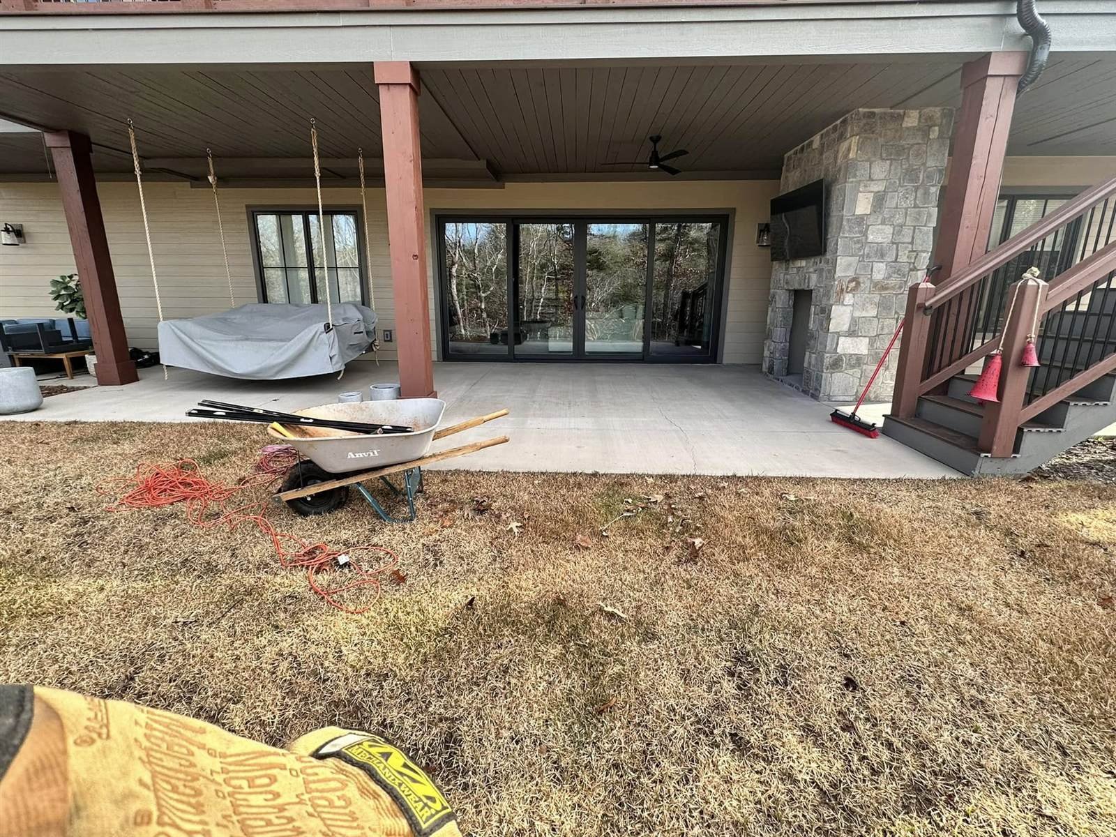 Covered patio under construction with stone fireplace and porch swing