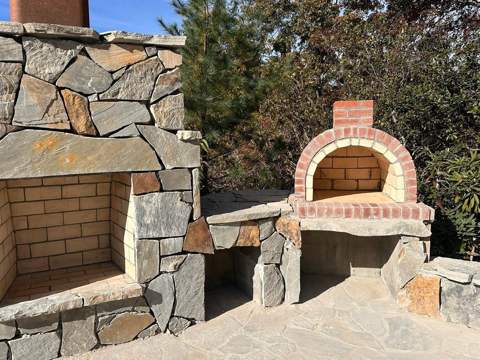 Stone fireplace and arched brick pizza oven under construction