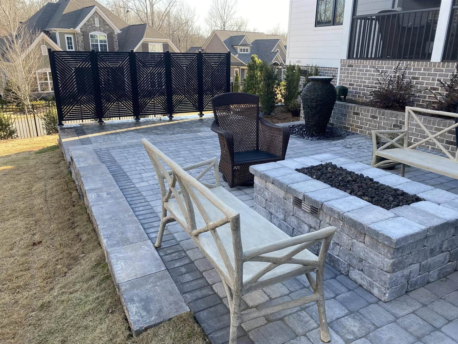 Modern paver patio with linear fire pit and black spillover urn water feature