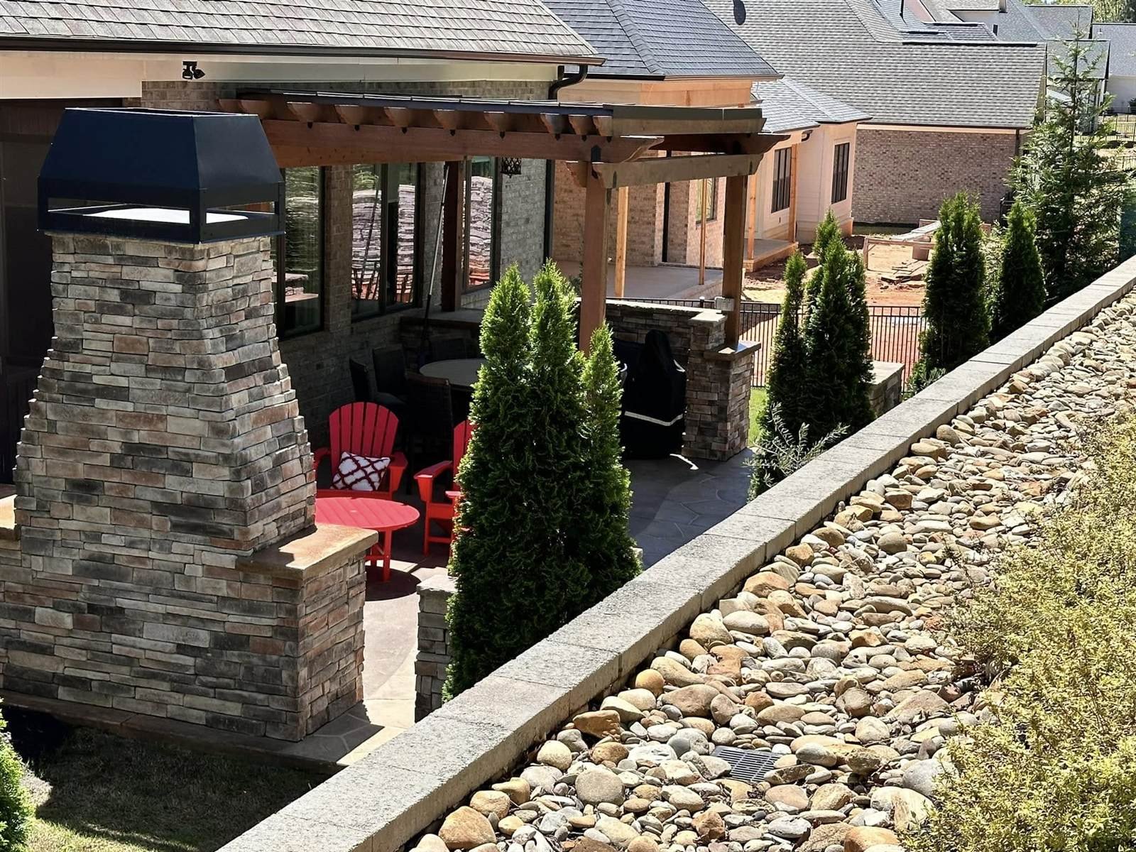 Stone outdoor fireplace with cedar pergola and patio seating area