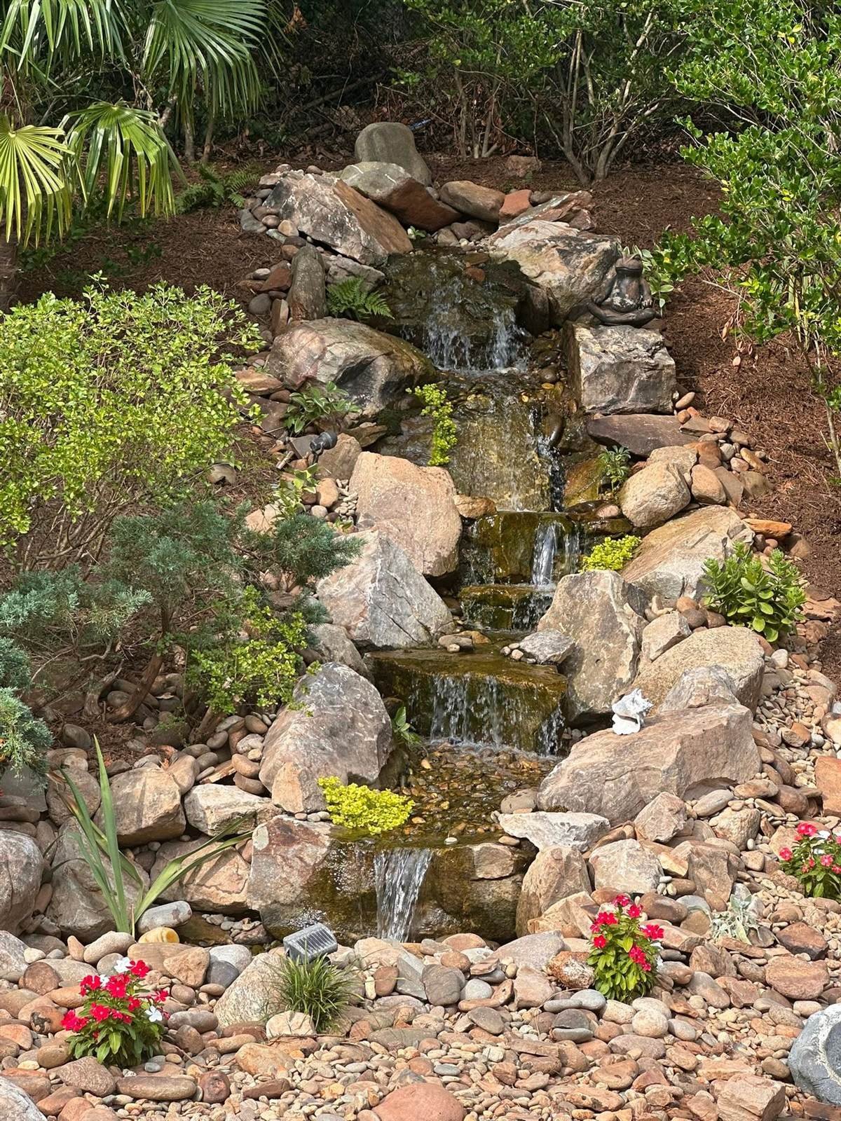 Multi-tier natural stone waterfall with flowering plants