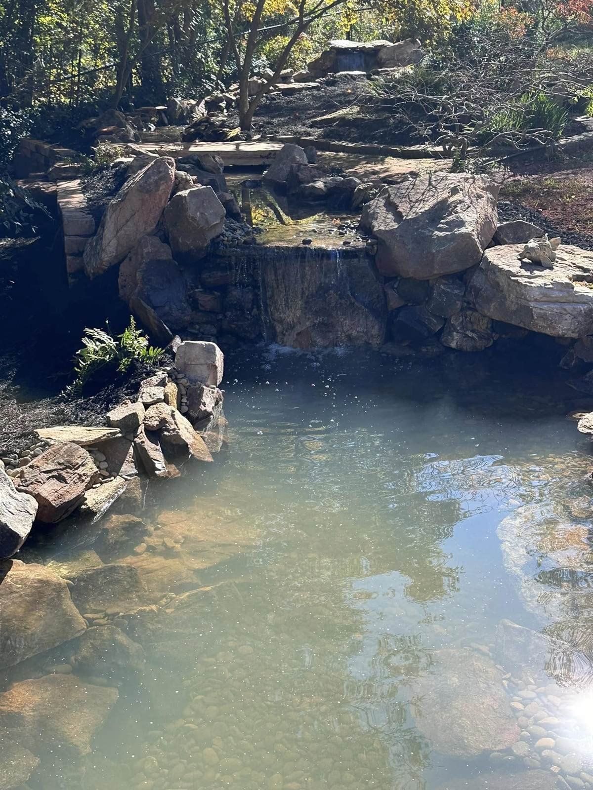 Wide natural pond and waterfall surrounded by boulders