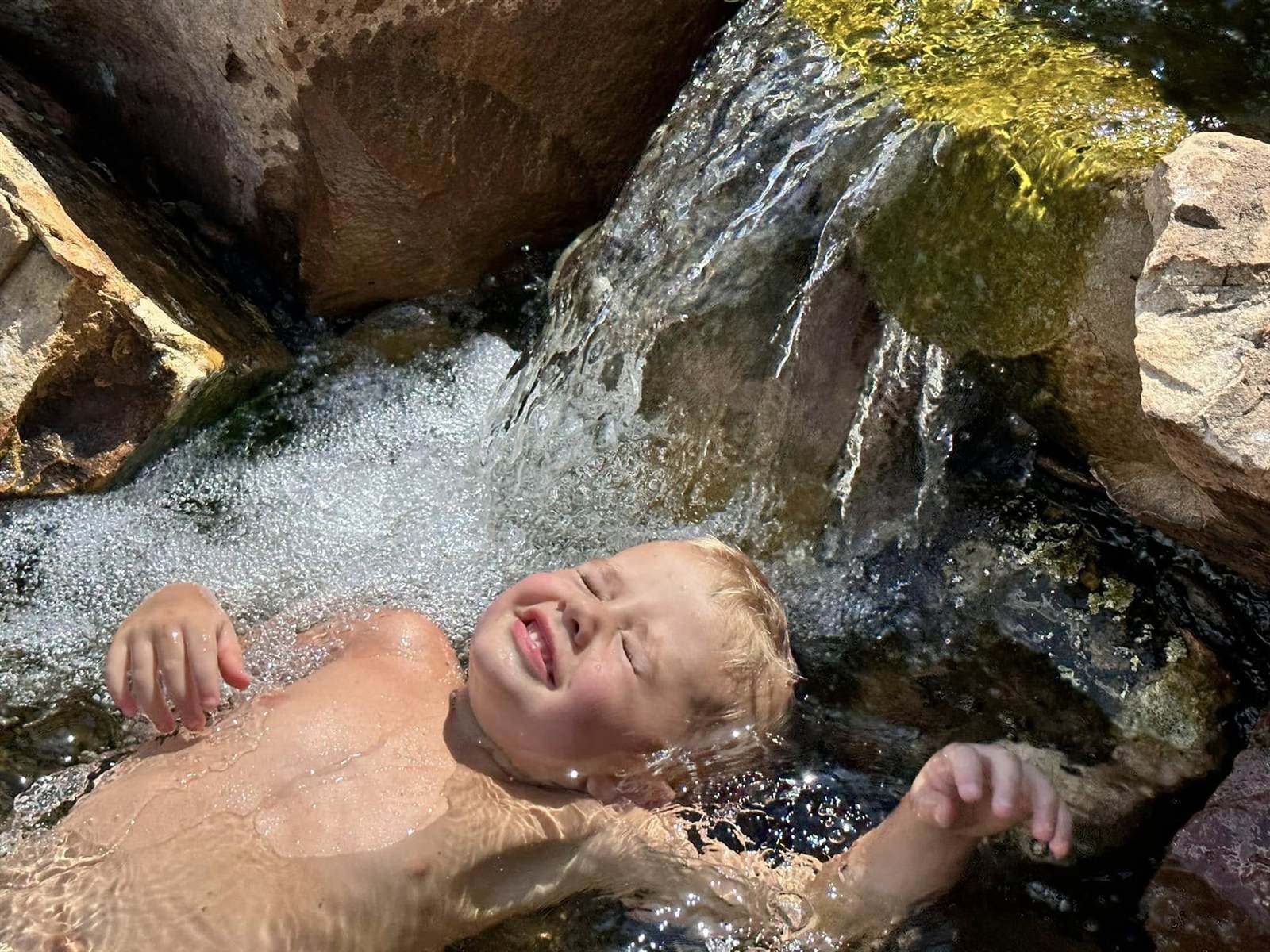 Child playing in a backyard waterfall stream