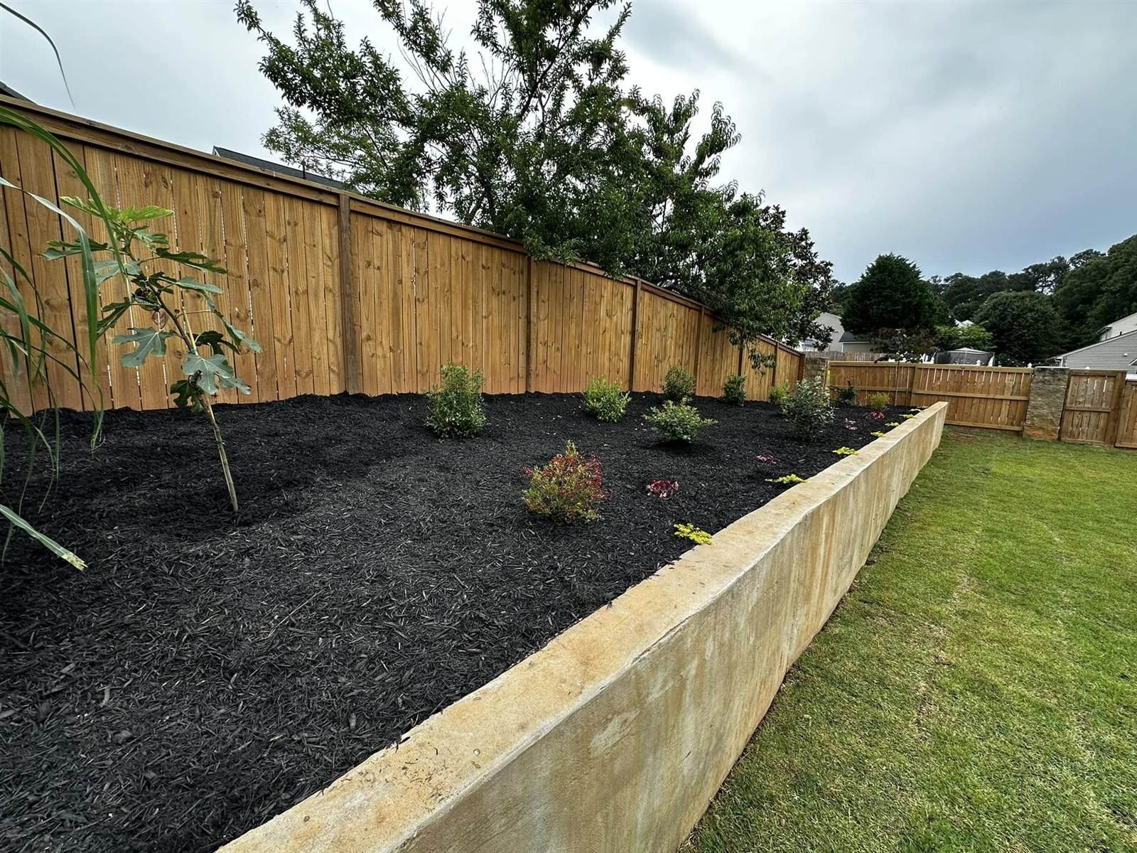 Backyard after Luxury Landscapes installed a retaining wall, sod and planting beds